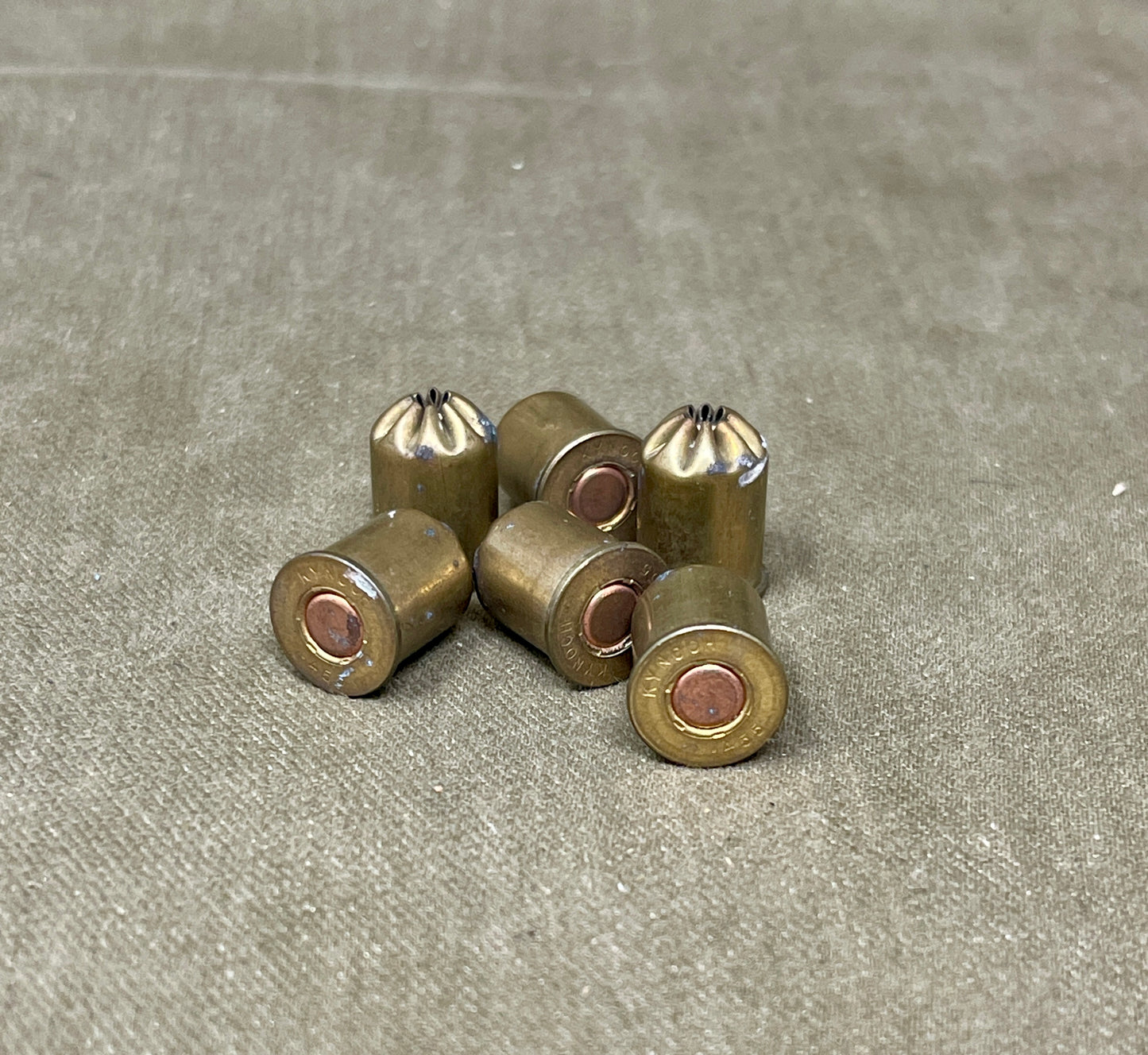 Set of six brass bullet casings on a gray surface