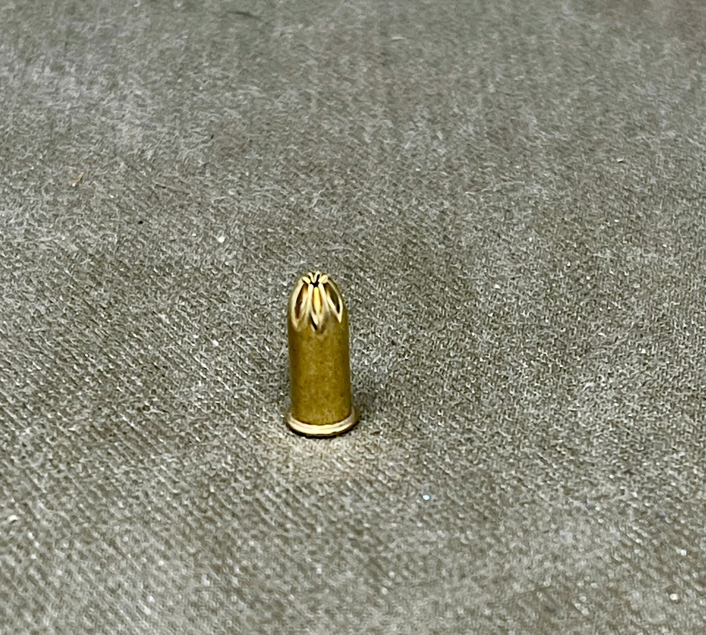 Small brass bullet-shaped object on a textured gray surface