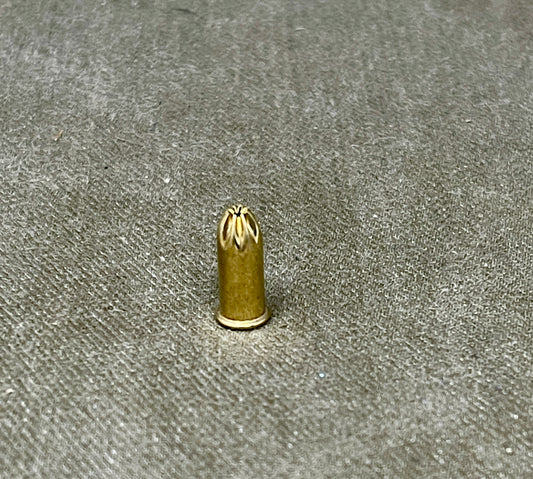 Small brass bullet-shaped object on a textured gray surface