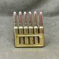 Brass bullet casing holder with six brass bullets on a gray background