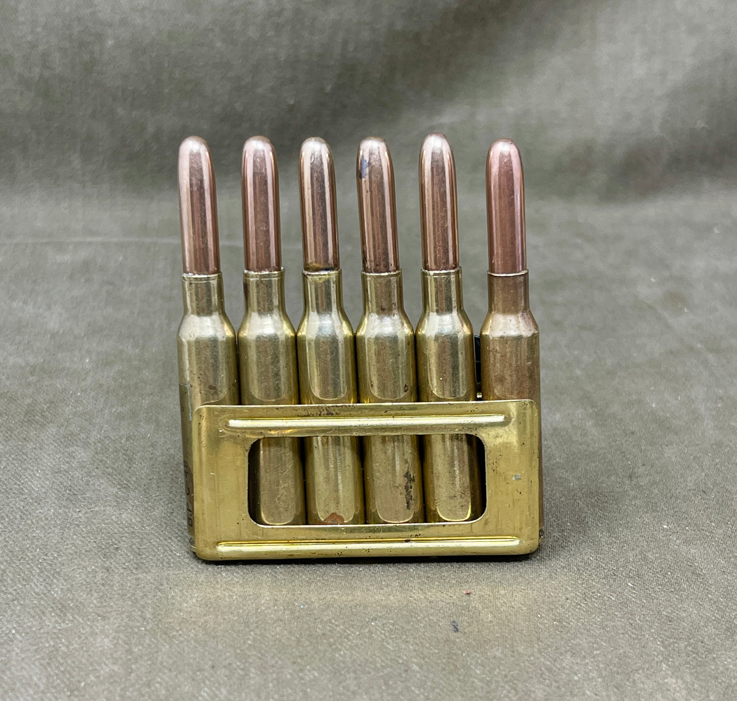 Brass bullet casing holder with six brass bullets on a gray background