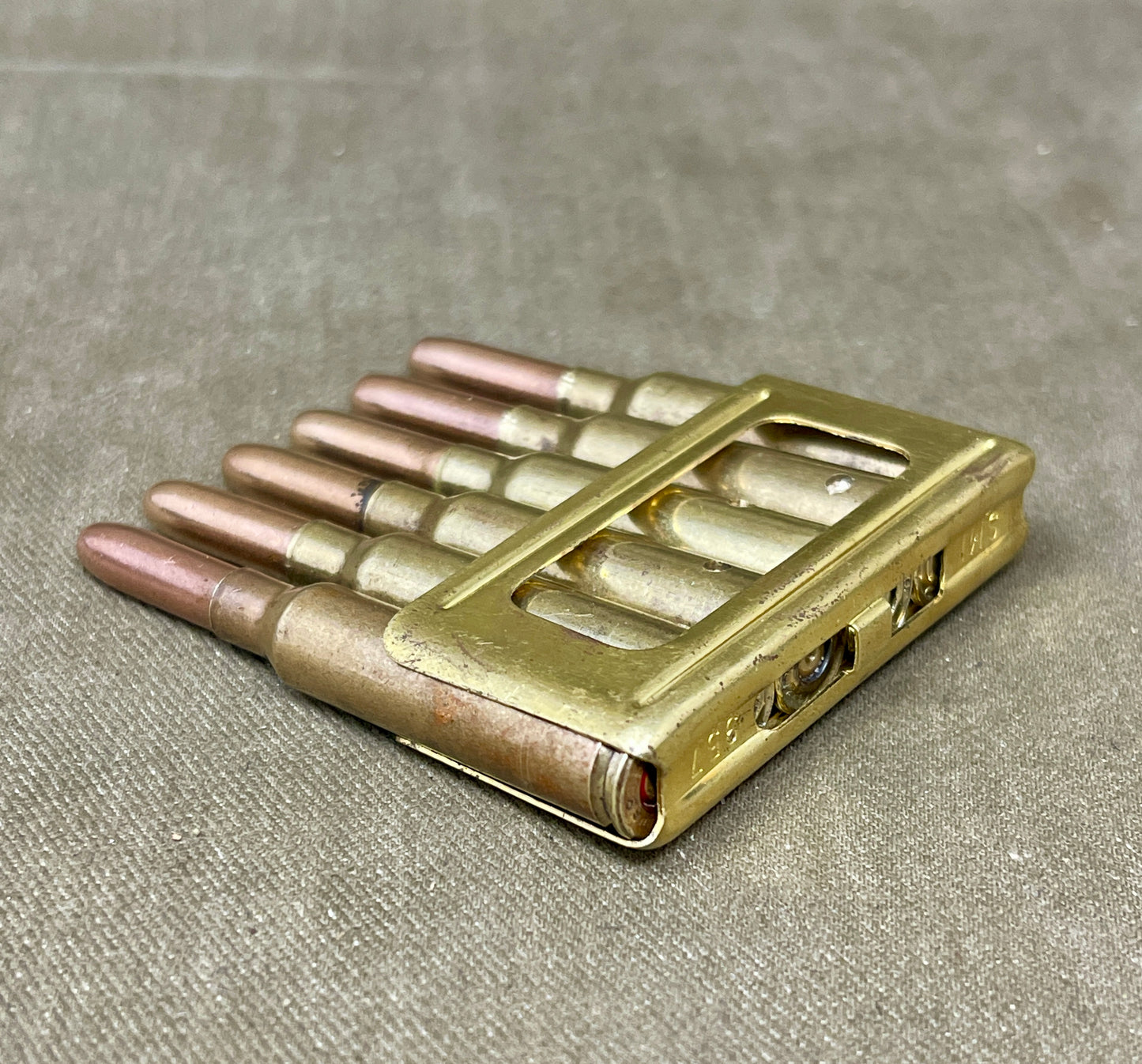 Metallic ammunition clip on a textured gray surface