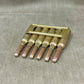 Set of six brass drill bits in a holder on a gray fabric background
