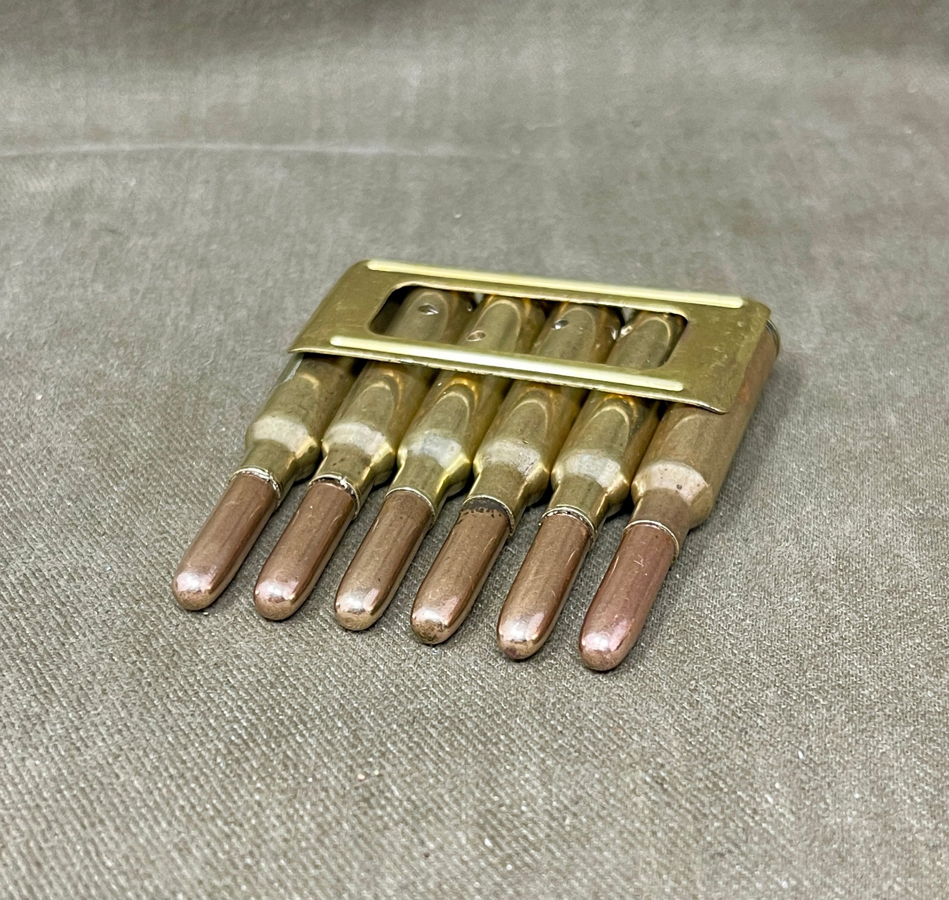 Set of six brass drill bits in a holder on a gray fabric background