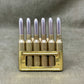 Brass ammunition clip with six silver bullets on a gray background