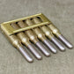 Set of six metallic drill bits in a holder on a textured surface