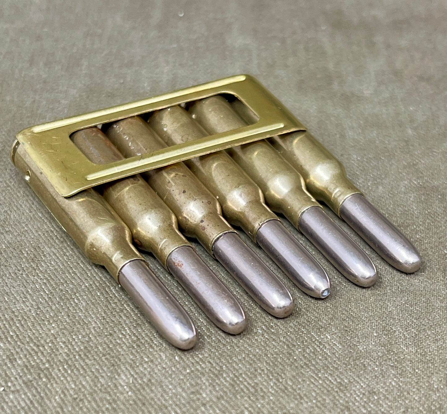 Set of six metallic drill bits in a holder on a textured surface