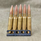 Five rifle bullets in a holder on a textured surface