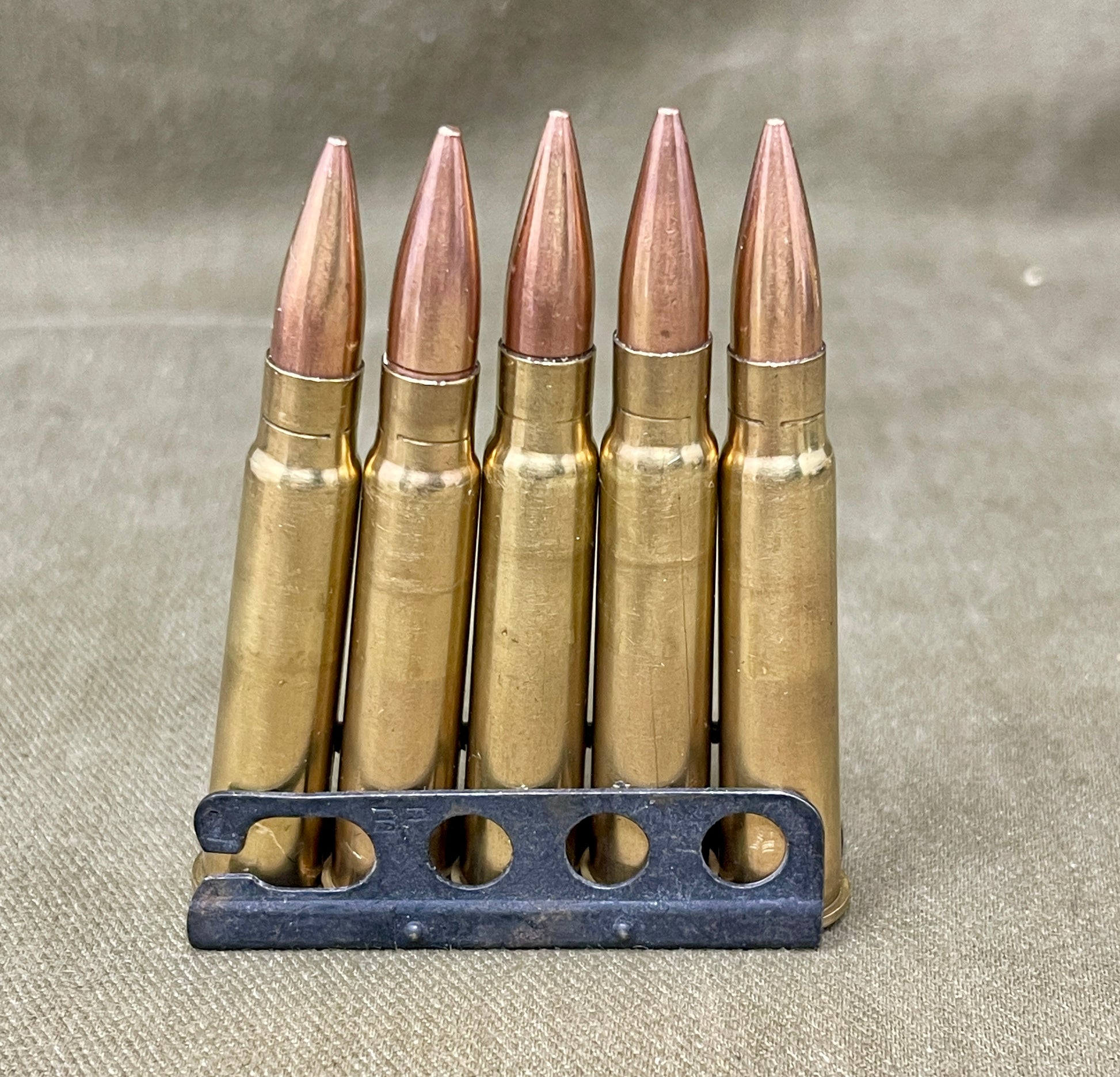 Five rifle bullets in a holder on a textured surface
