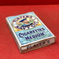 An empty packet for 10 Player's Medium Navy Cut cigarettes. The front has an ocean scene and a sailor framed in a life belt.