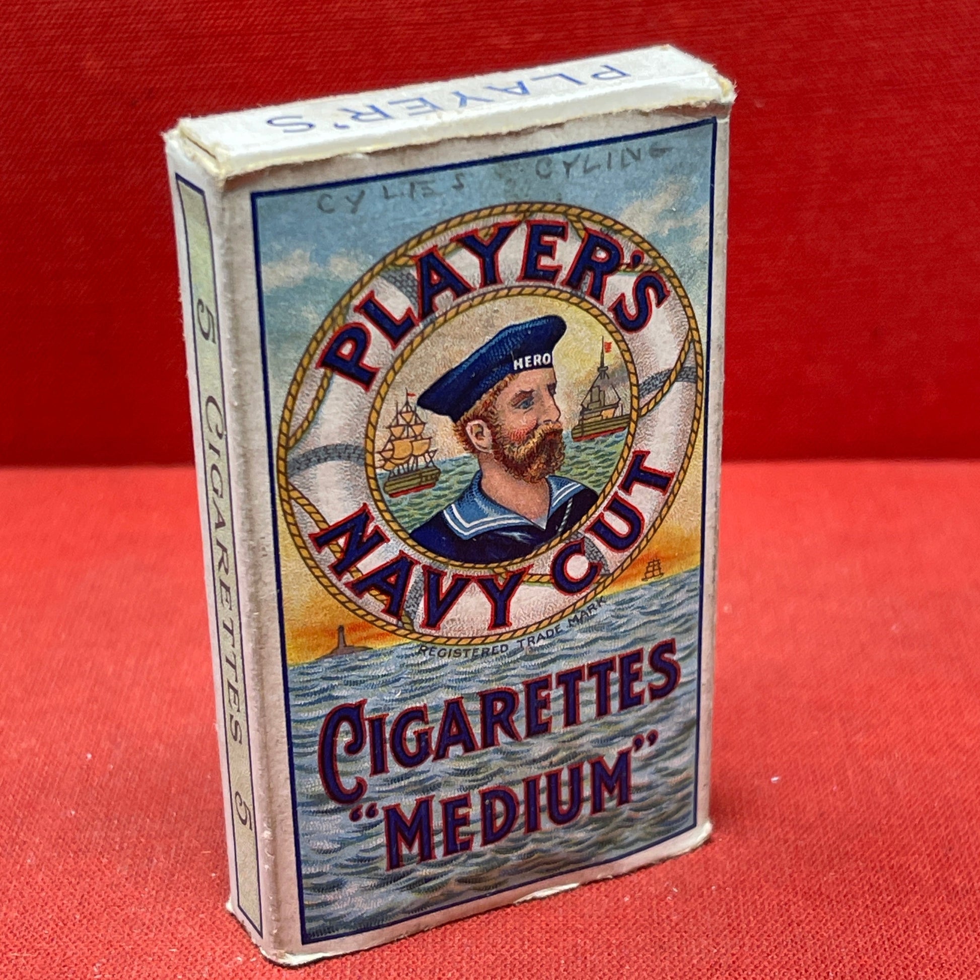 An empty packet for 10 Player's Medium Navy Cut cigarettes. The front has an ocean scene and a sailor framed in a life belt.