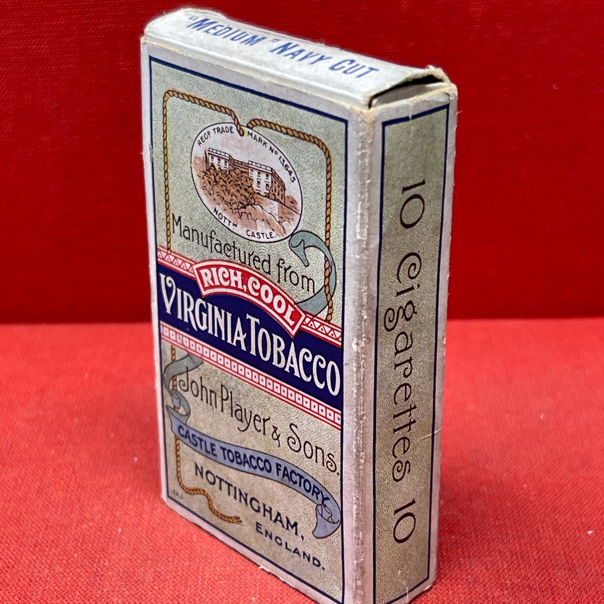 An empty packet for 10 Player's Medium Navy Cut cigarettes. The front has an ocean scene and a sailor framed in a life belt.