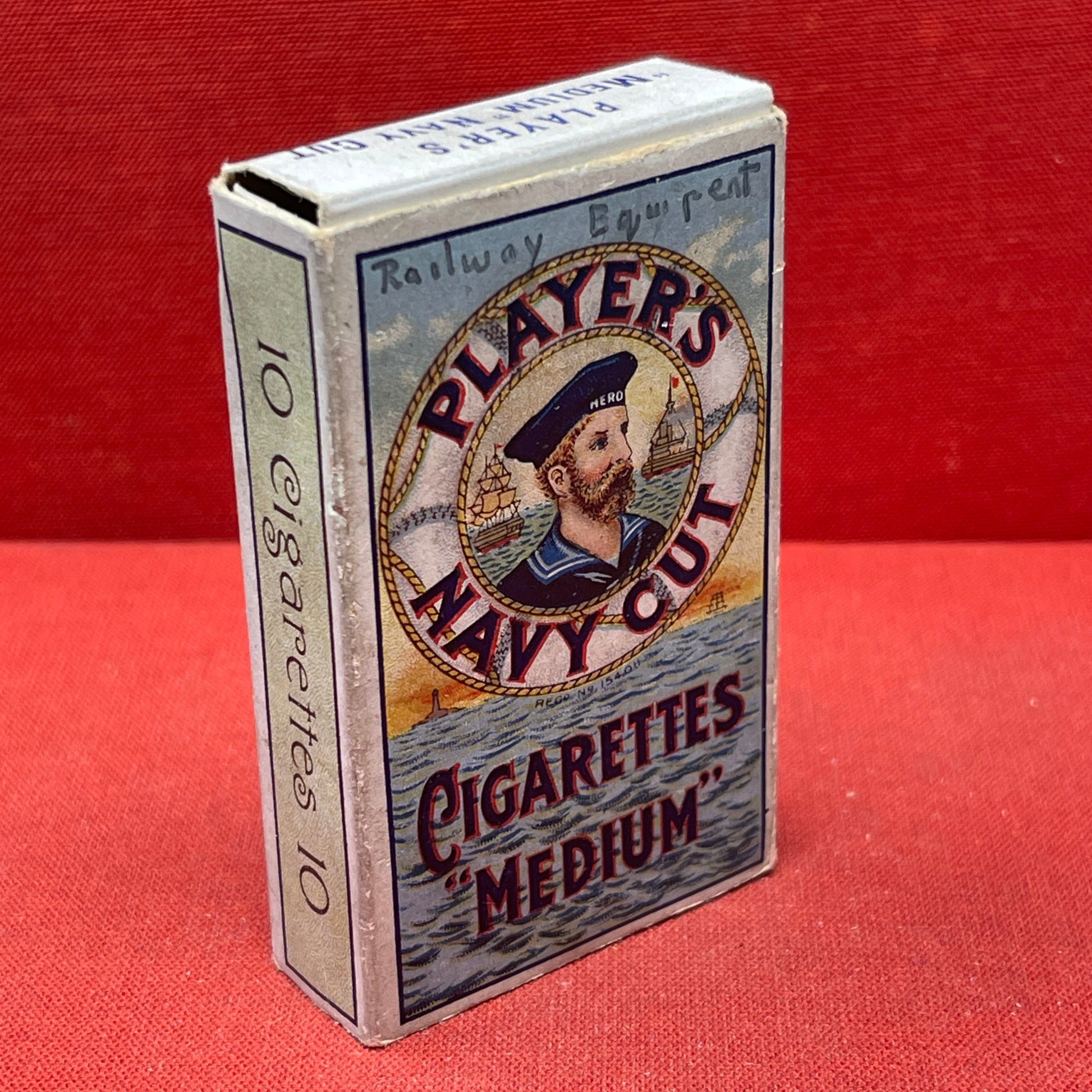 An empty packet for 10 Player's Medium Navy Cut cigarettes. The front has an ocean scene and a sailor framed in a life belt.