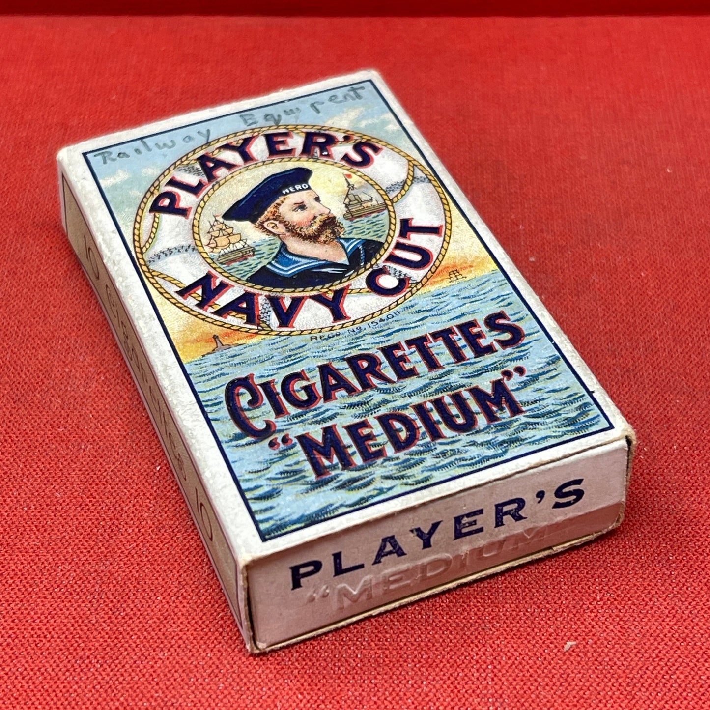 An empty packet for 10 Player's Medium Navy Cut cigarettes. The front has an ocean scene and a sailor framed in a life belt.