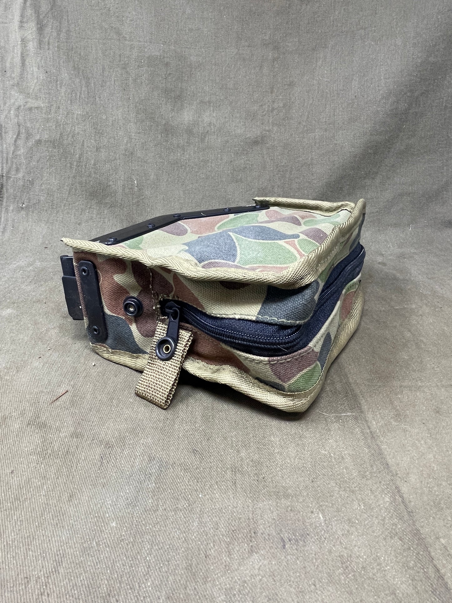 Australian Army LMG pouch, featuring the iconic Australian pattern camouflage. This pouch is designed for durability and functionality, constructed from rugged, heavy-duty materials capable of withstanding harsh field conditions. Its distinctive camouflage pattern ensures effective concealment across a variety of Australian terrains, including dense bushland and arid environments.