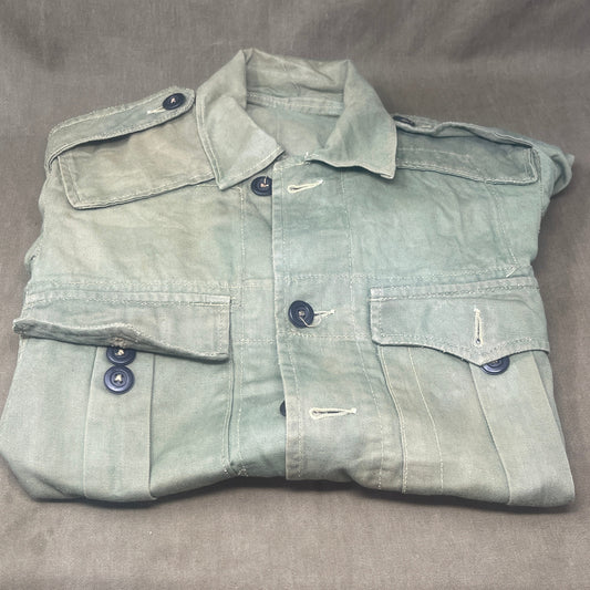 This original 1951-dated British Army Jungle Green Bush Jacket is a superb example of early post-war tropical combat clothing, manufactured by the reputable N. Lotery & Co. Ltd. Made from sturdy, breathable cotton in classic Jungle Green, this jacket was designed for use in humid and challenging environments such as Malaya and other post-war theatres of operation.

The jacket is in excellent condition, showing minimal signs of wear, with its color, stitching, and structural integrity all remarkably well-pre