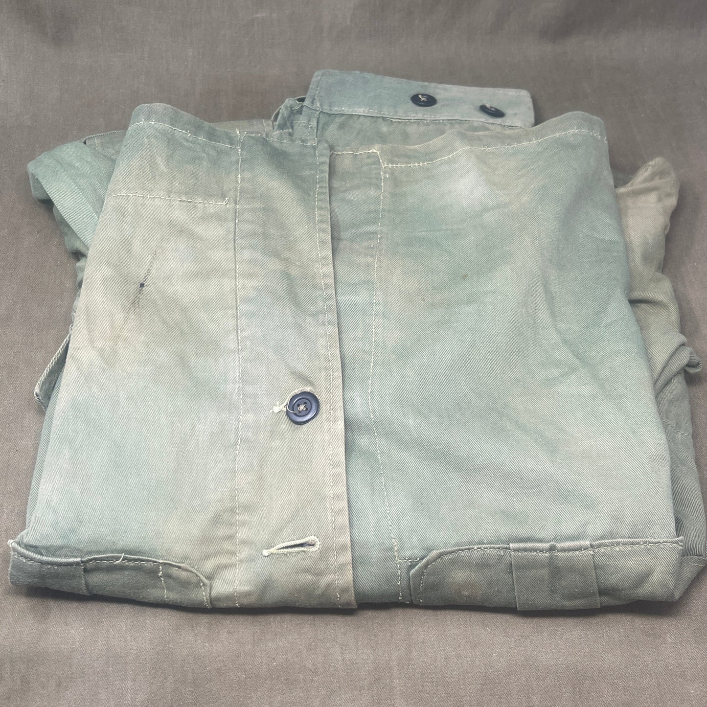 This original 1951-dated British Army Jungle Green Bush Jacket is a superb example of early post-war tropical combat clothing, manufactured by the reputable N. Lotery & Co. Ltd. Made from sturdy, breathable cotton in classic Jungle Green, this jacket was designed for use in humid and challenging environments such as Malaya and other post-war theatres of operation.

The jacket is in excellent condition, showing minimal signs of wear, with its color, stitching, and structural integrity all remarkably well-pre