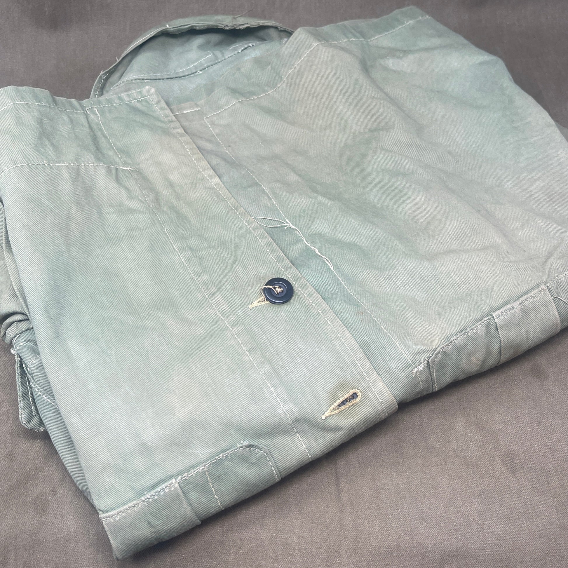 This original 1951-dated British Army Jungle Green Bush Jacket is a superb example of early post-war tropical combat clothing, manufactured by the reputable N. Lotery & Co. Ltd. Made from sturdy, breathable cotton in classic Jungle Green, this jacket was designed for use in humid and challenging environments such as Malaya and other post-war theatres of operation.

The jacket is in excellent condition, showing minimal signs of wear, with its color, stitching, and structural integrity all remarkably well-pre