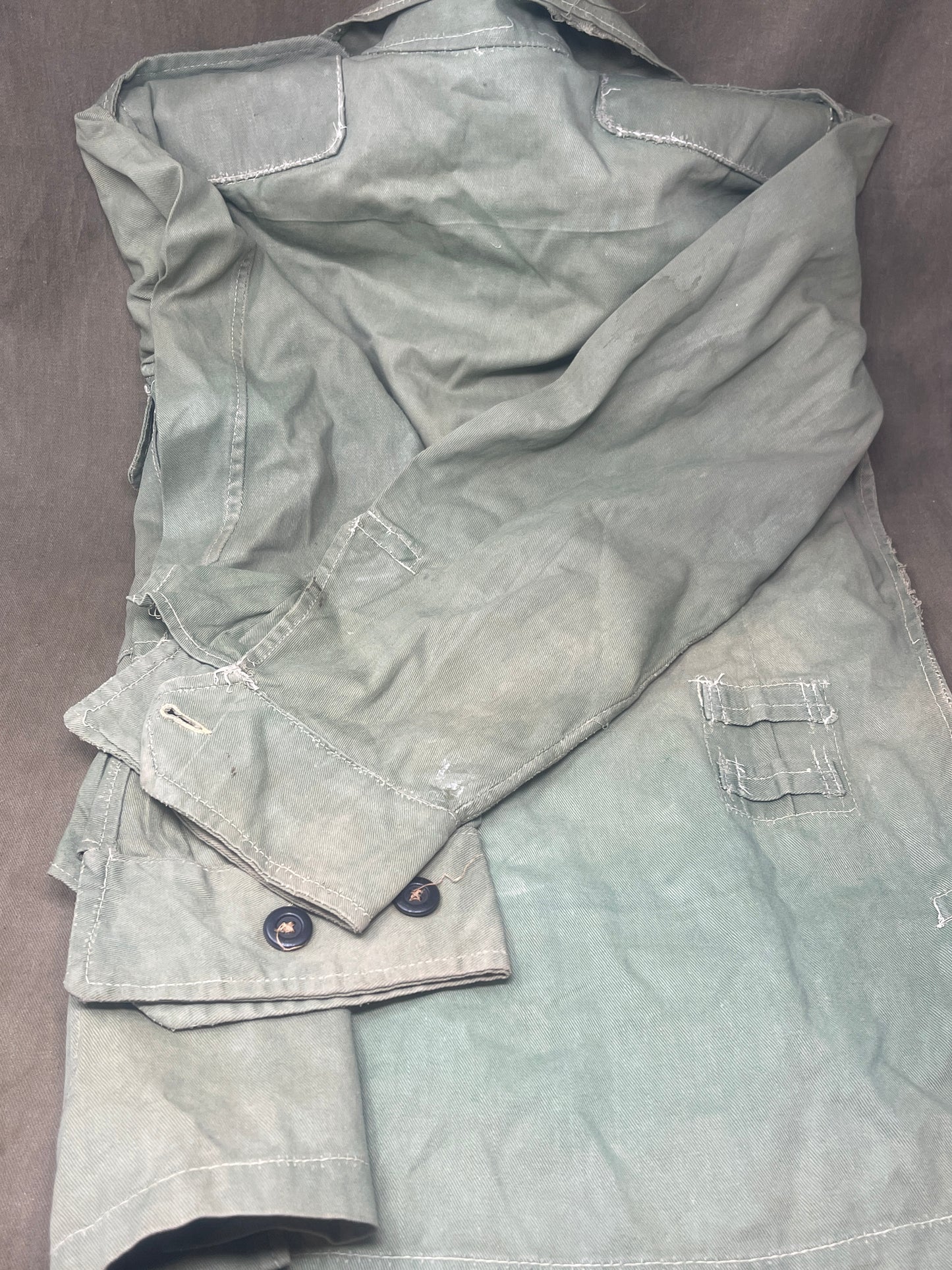 This original 1951-dated British Army Jungle Green Bush Jacket is a superb example of early post-war tropical combat clothing, manufactured by the reputable N. Lotery & Co. Ltd. Made from sturdy, breathable cotton in classic Jungle Green, this jacket was designed for use in humid and challenging environments such as Malaya and other post-war theatres of operation.

The jacket is in excellent condition, showing minimal signs of wear, with its color, stitching, and structural integrity all remarkably well-pre
