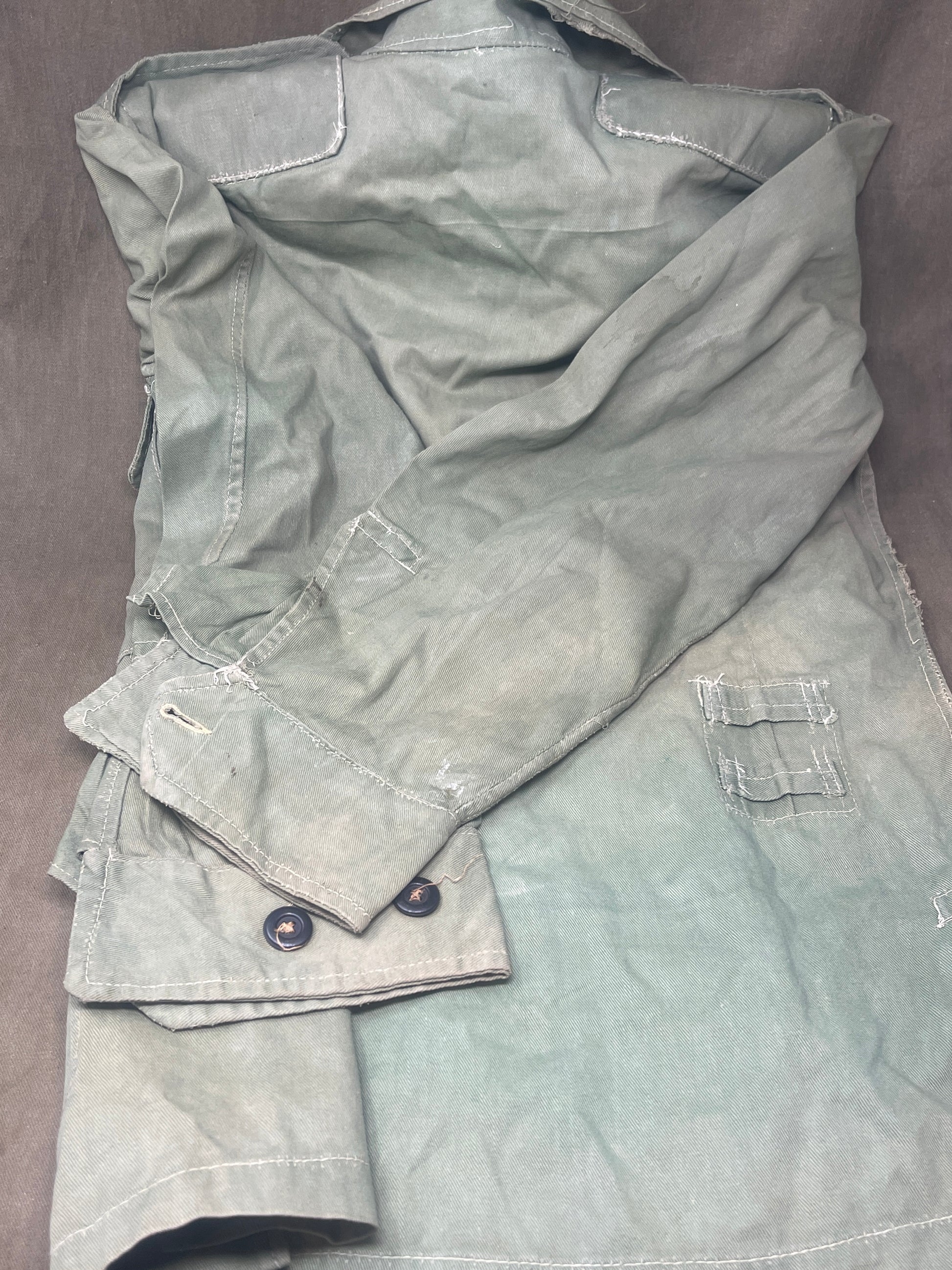 This original 1951-dated British Army Jungle Green Bush Jacket is a superb example of early post-war tropical combat clothing, manufactured by the reputable N. Lotery & Co. Ltd. Made from sturdy, breathable cotton in classic Jungle Green, this jacket was designed for use in humid and challenging environments such as Malaya and other post-war theatres of operation.

The jacket is in excellent condition, showing minimal signs of wear, with its color, stitching, and structural integrity all remarkably well-pre