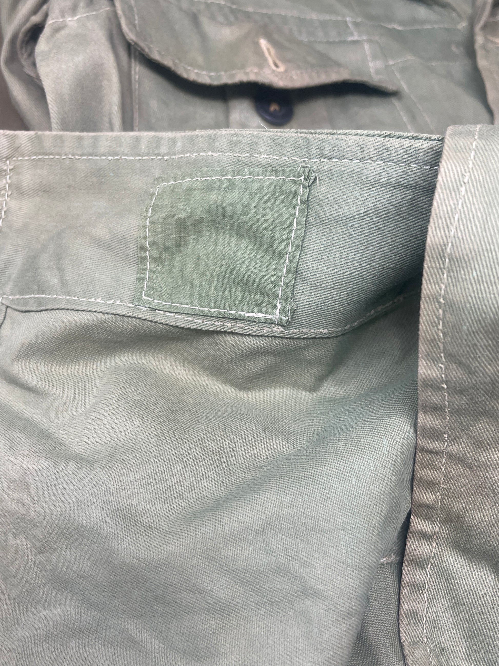 This original 1951-dated British Army Jungle Green Bush Jacket is a superb example of early post-war tropical combat clothing, manufactured by the reputable N. Lotery & Co. Ltd. Made from sturdy, breathable cotton in classic Jungle Green, this jacket was designed for use in humid and challenging environments such as Malaya and other post-war theatres of operation.

The jacket is in excellent condition, showing minimal signs of wear, with its color, stitching, and structural integrity all remarkably well-pre