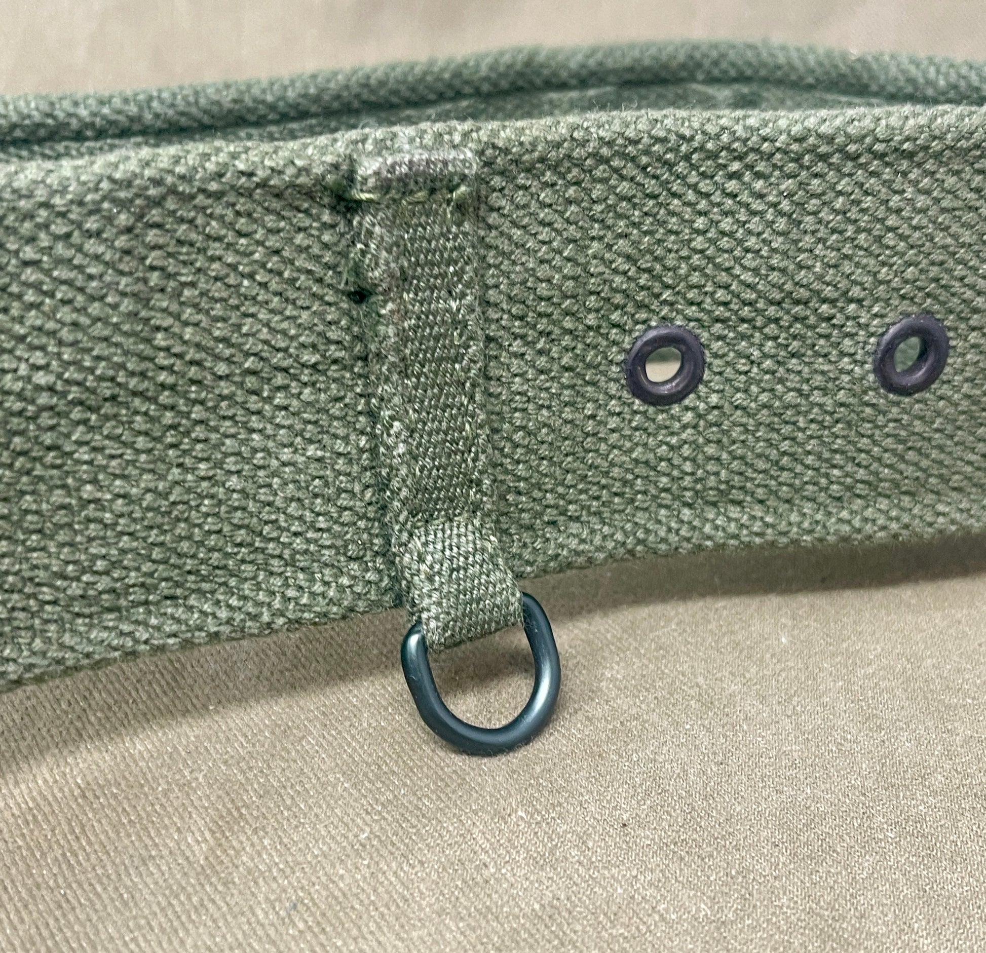 Close-up of a green belt with metal rings on a beige background