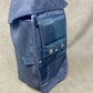 Blue bag with multiple pockets and buttons on a beige background