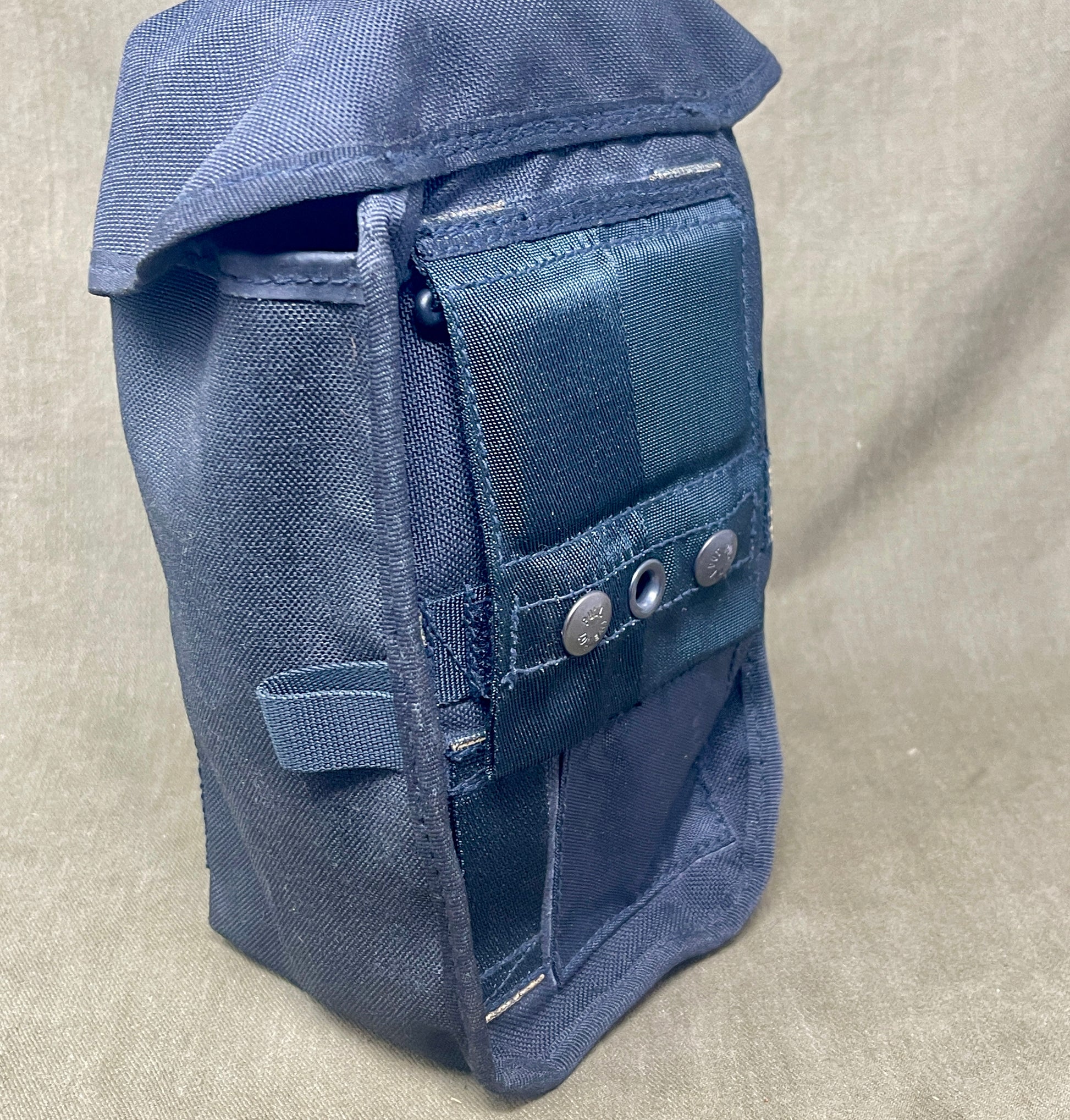 Blue bag with multiple pockets and buttons on a beige background