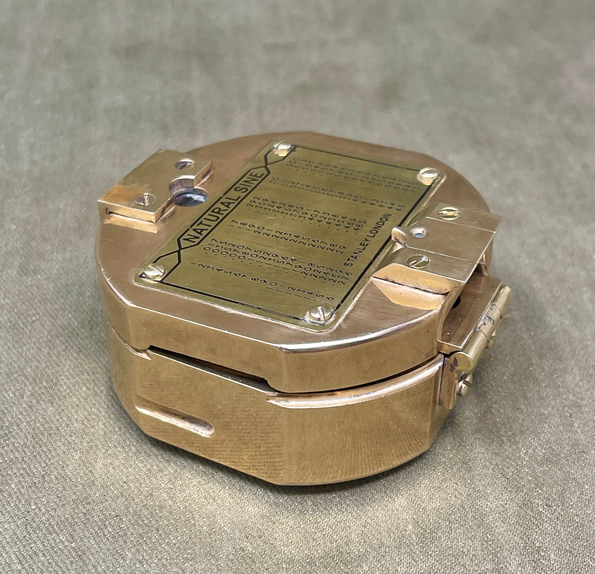 Brass pocket watch with engraved text on a gray background