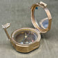 Metallic compass with open lid on a gray surface