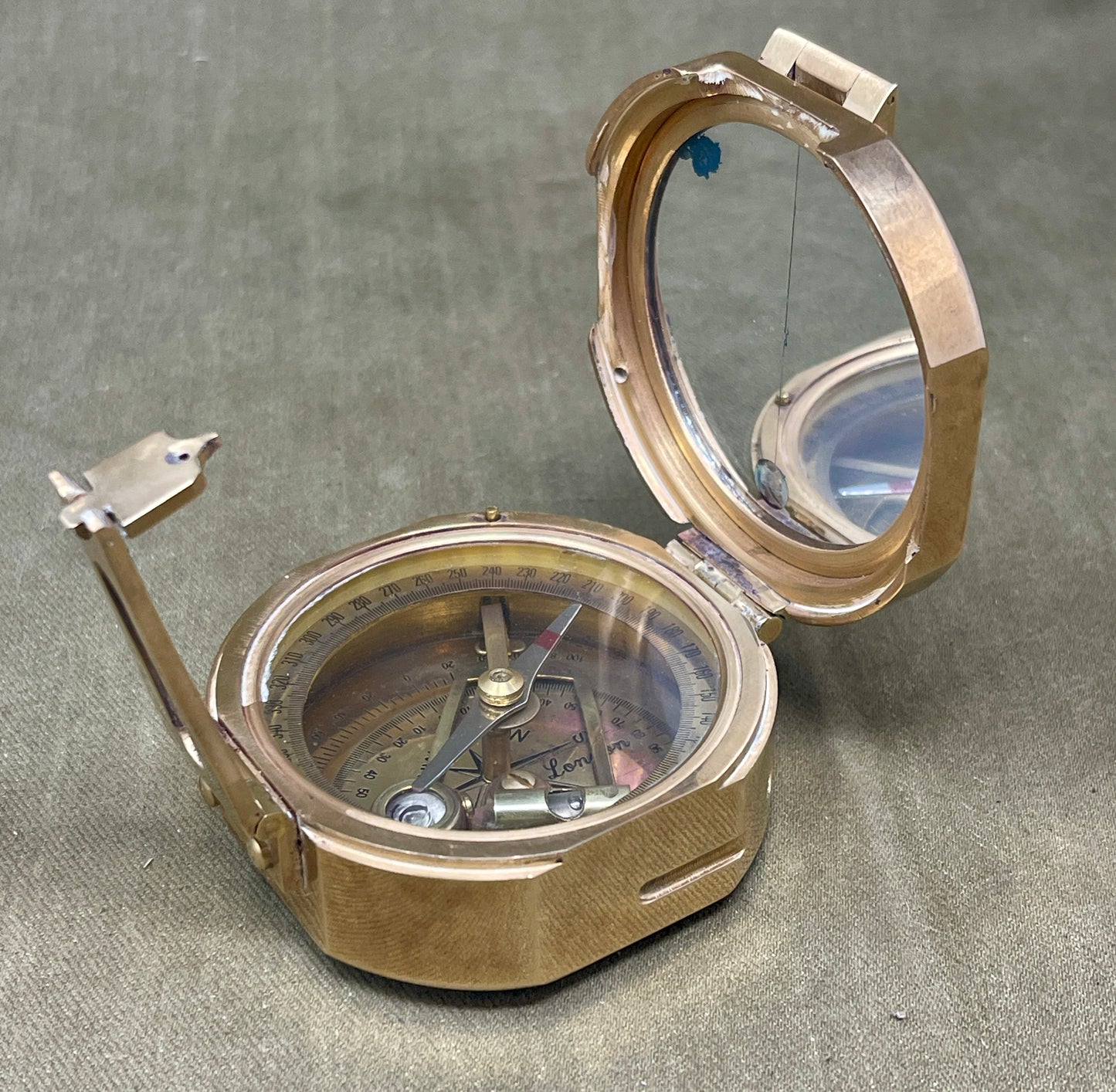 Metallic compass with open lid on a gray surface