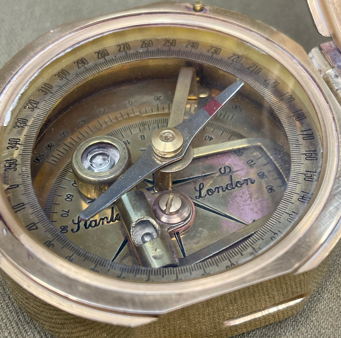 Close-up of an antique compass with 'London' and 'Stamle' branding.