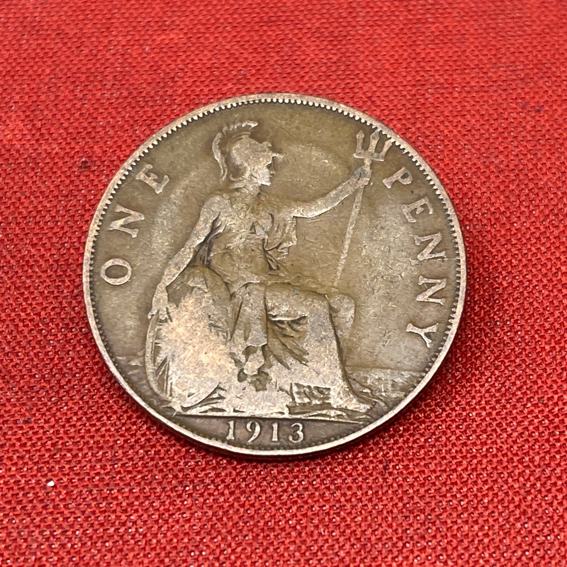 On the obverse side of the coin, you will find a portrait of King George V facing left, accompanied by the inscription "GEORGIVS V DEI GRA BRITT OMN REX FID DEF IND IMP." This Latin inscription translates to "George V by the Grace of God, King of all the Britains, Defender of the Faith, Emperor of India." The reverse side features the denomination "ONE PENNY and the year of minting.