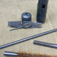 Set of gun cleaning tools including a brush, rod, and other components on a textured surface.