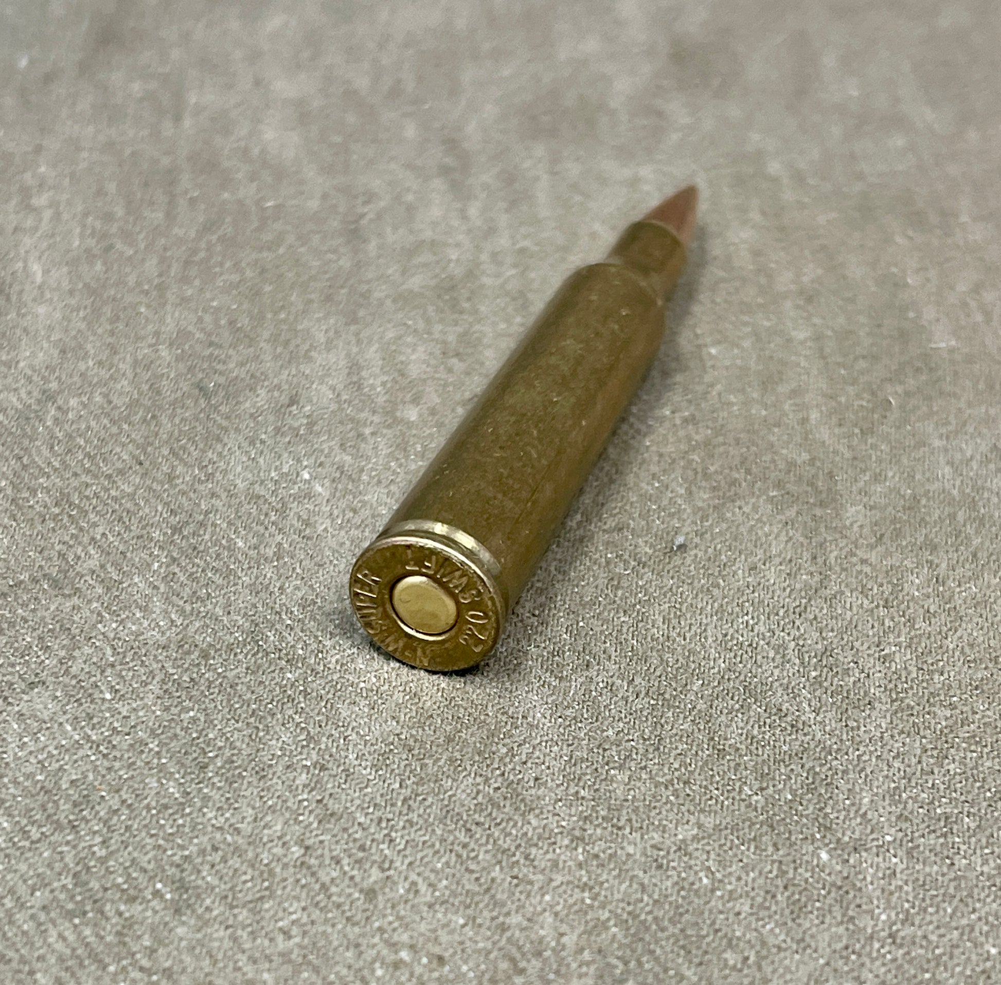 This is an original WW2-era Super .220 Swift round, professionally rendered completely inert for safe collecting and display purposes. The cartridge retains its original full metal jacketed projectile and brass casing, featuring the correct wartime Super headstamp. It has been expertly deactivated, with the primer replaced by an inert one and all propellant removed. The .220 Swift was known for its high velocity and flat trajectory, originally developed in the 1930s and occasionally used for experimental or