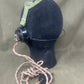 Black gas mask canister with green strap on a beige background