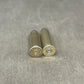 Two brass shotgun shells on a gray textured surface