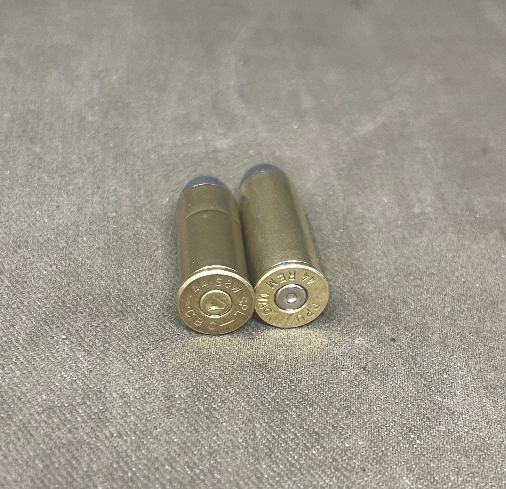 Two brass shotgun shells on a gray textured surface
