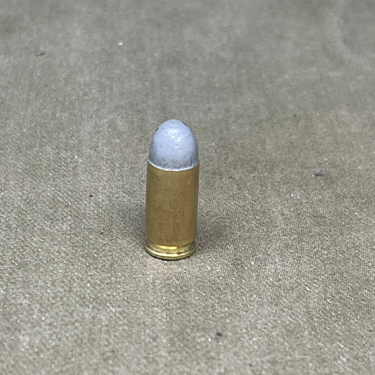 Bullet casing with a white bullet on a gray concrete surface