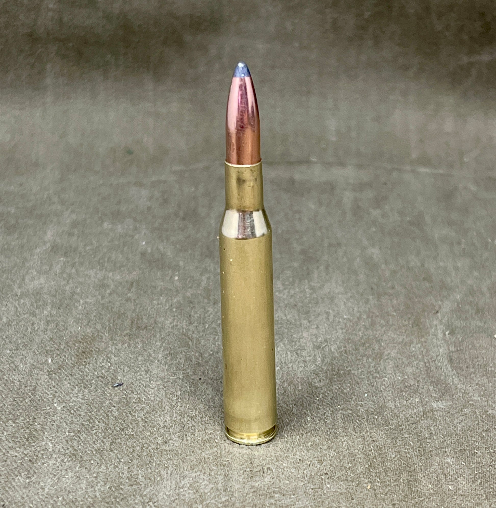 Bullet casing with a blue tip on a gray background