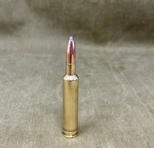 Bronze-colored rifle cartridge on a textured beige background