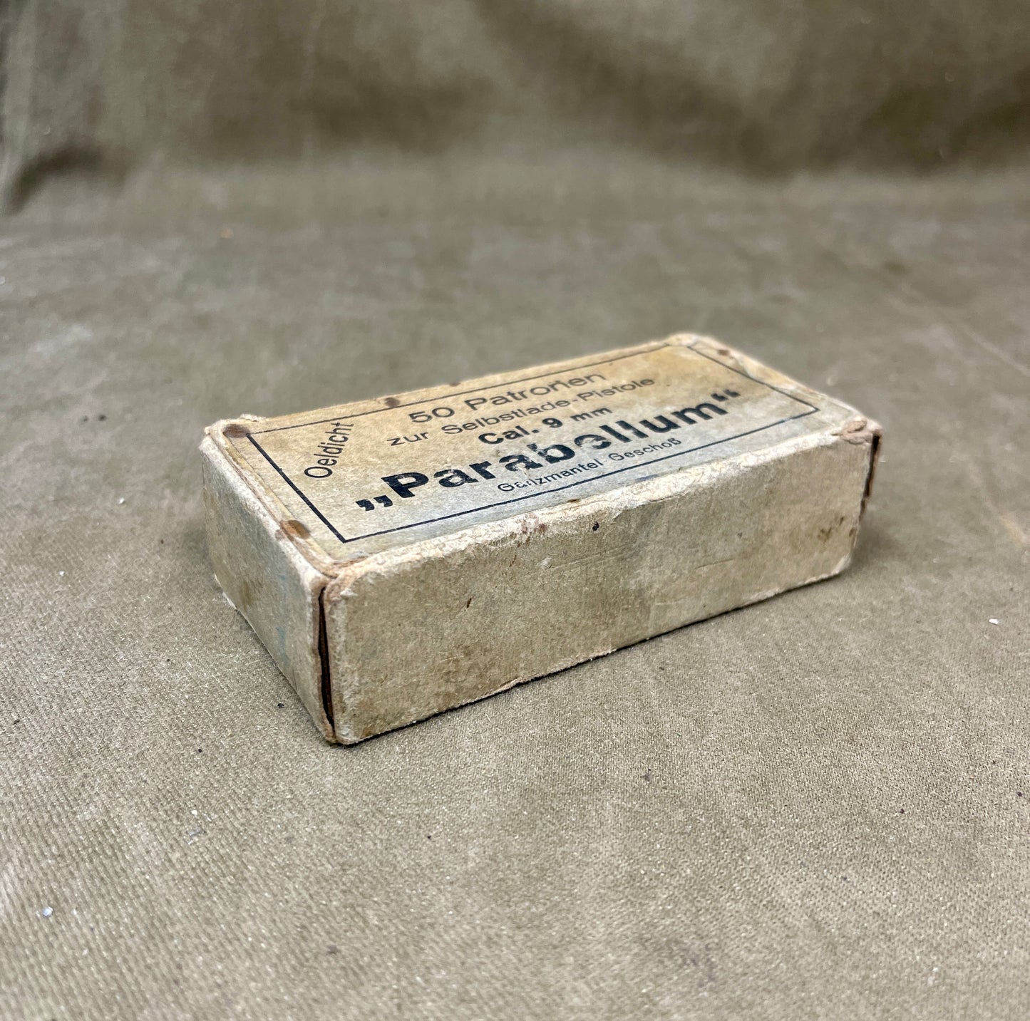 Vintage ammunition box labeled 'Parabellum' on a textured gray background
