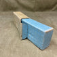 Blue ceramic object in a cardboard box on a textured surface