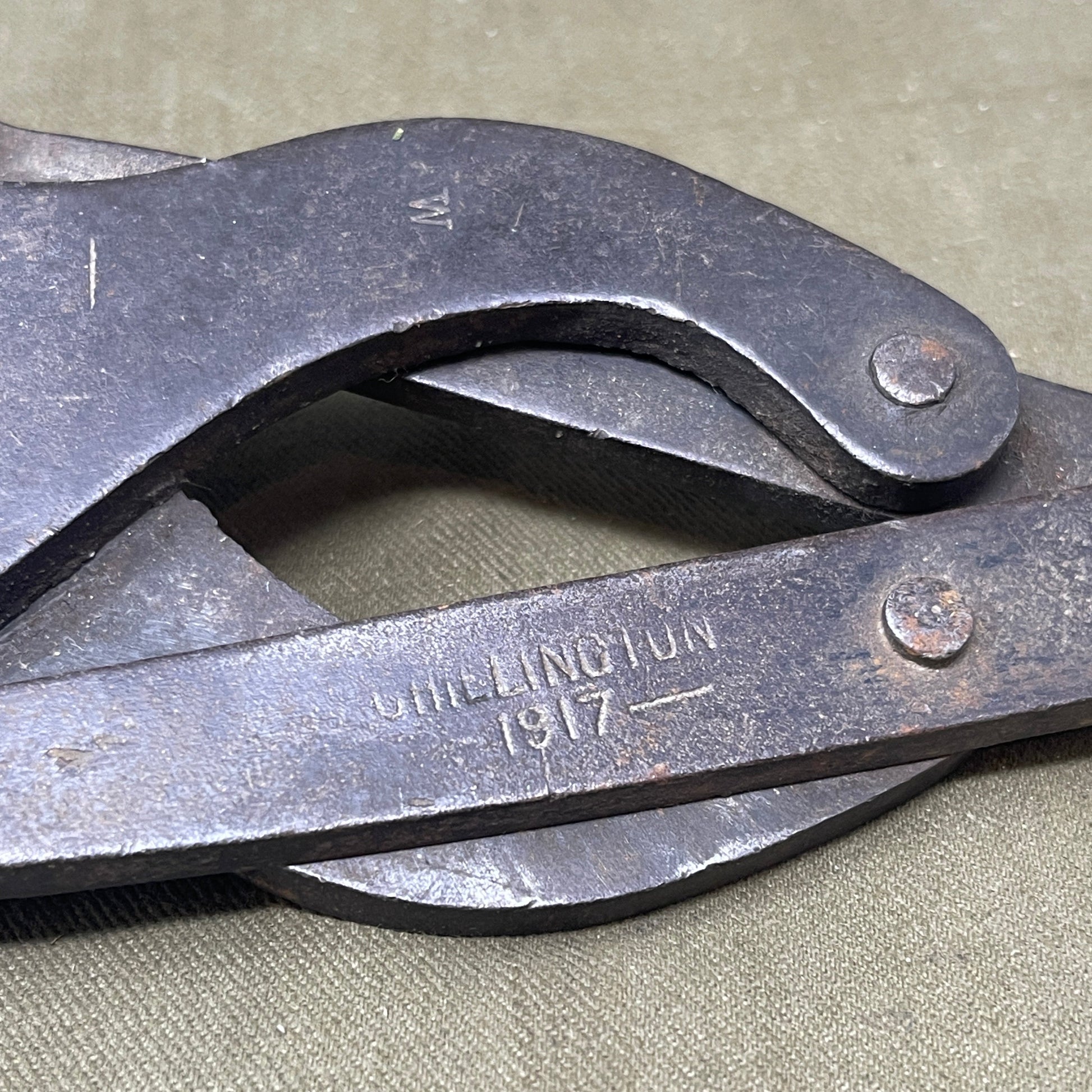 Original WWI British Wire Cutters, dated 1917 and made by Chillington, are durable steel tools with wooden handles, designed for cutting barbed wire in trench warfare. Essential for soldiers, these cutters reflect practical WWI engineering and are highly valued by collectors for their historical significance