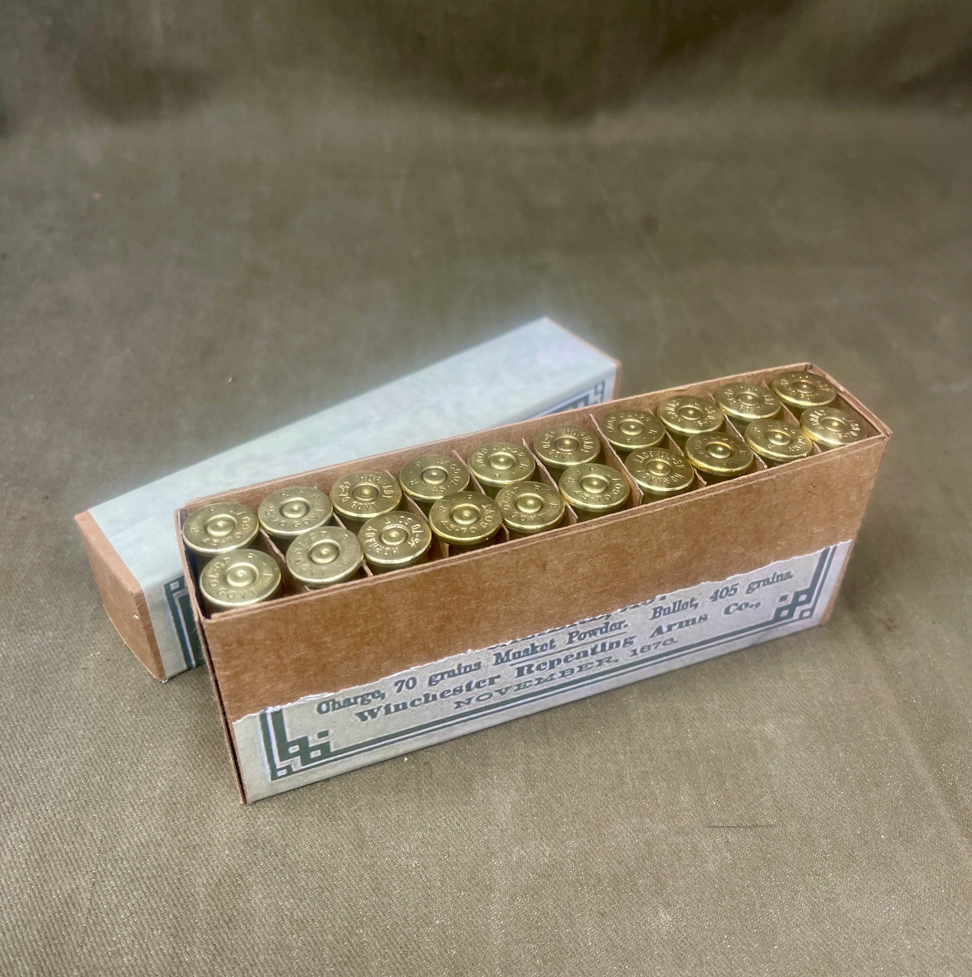Box of ammunition with brass casings on a textured surface