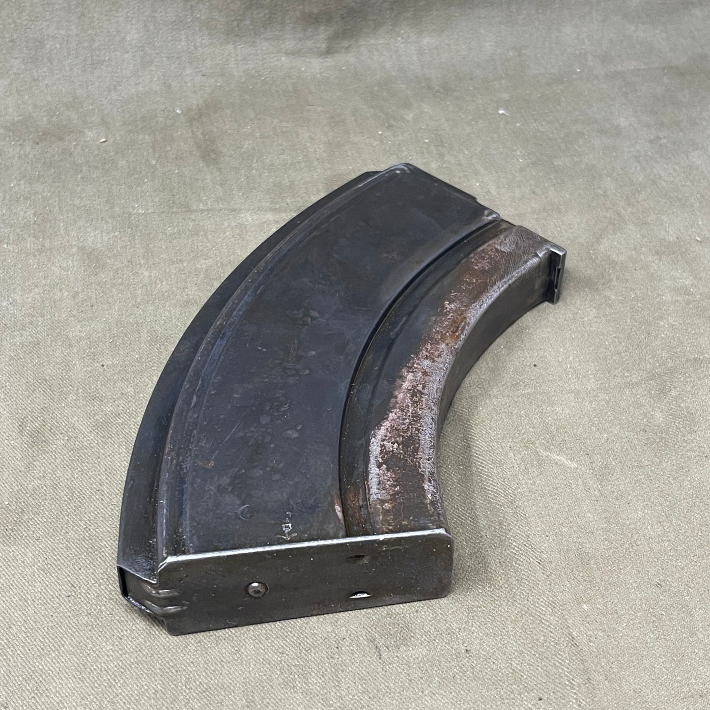 The Bren Gun magazine, iconic for its curved, box-like design, holds 30 rounds of .303 British ammo. Made from durable steel, it ensures reliable feeding and quick top-loading, crucial for mid-20th-century warfare. Renowned for its robustness and historical significance, it's prized by collectors and reenactors