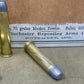 Two brass cartridges with blue tips on a surface in front of an old Winchester Repeating Arms box.