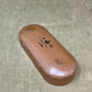 Brown eyeglass case with 'A.M.' branding on a textured surface