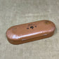 Brown eyeglass case with visible wear on a textured surface