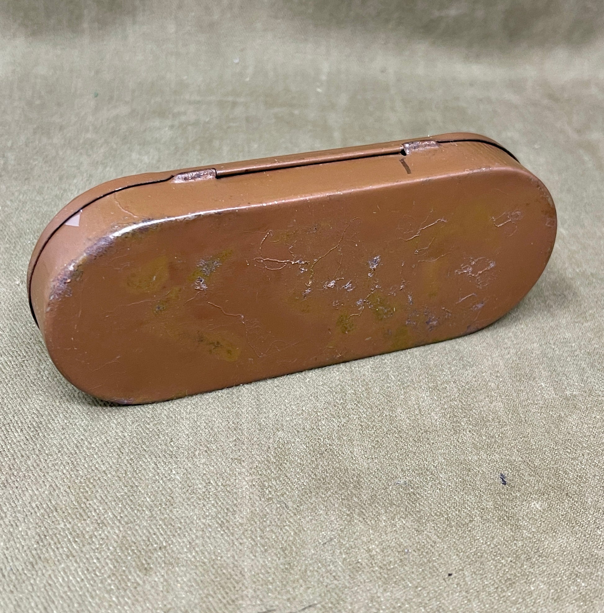Brown oval metal object on a beige fabric background